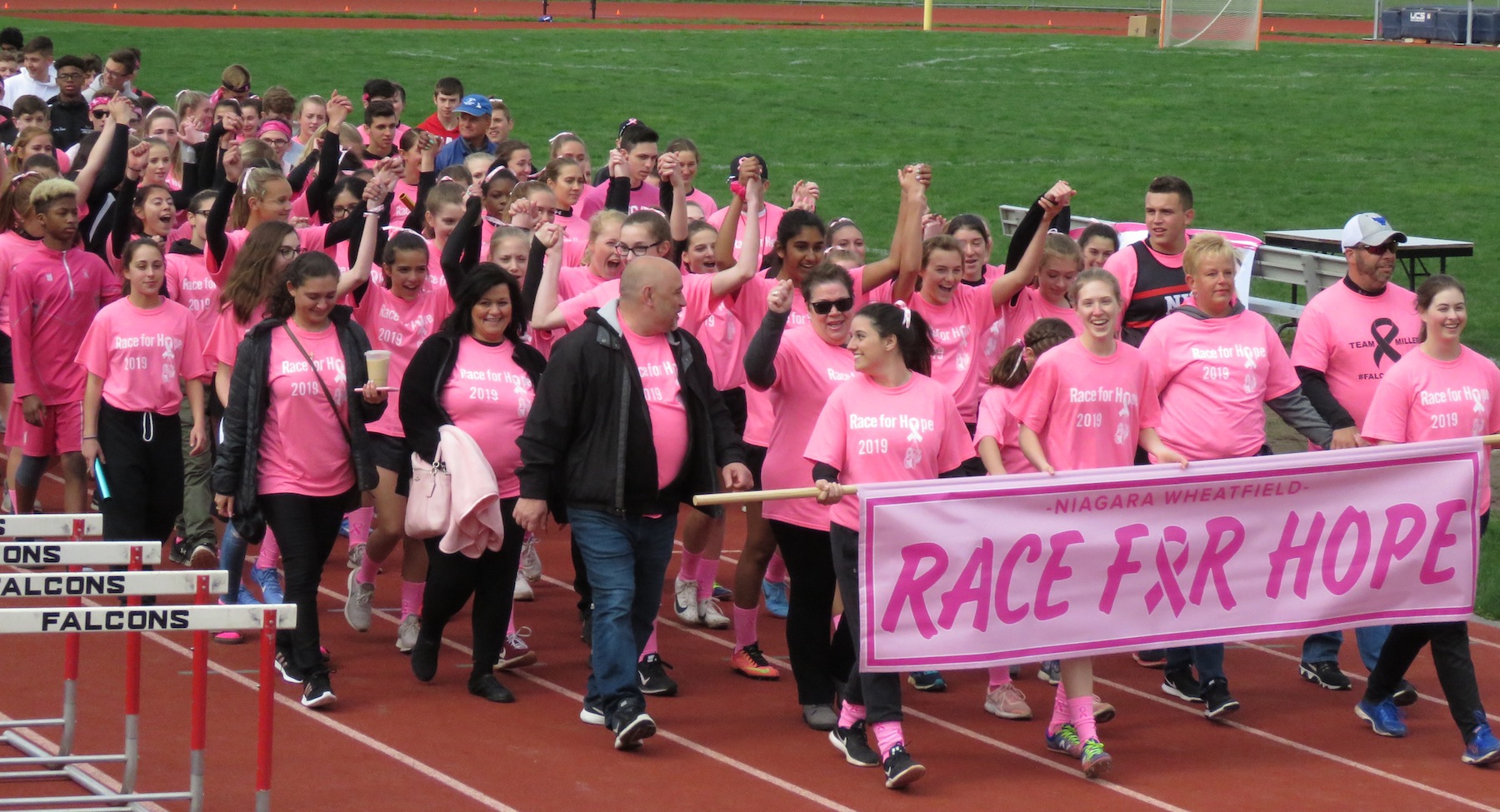 During an honorary lap, the Niagara-Wheatfield track and field team crosses the finish line alongside cancer survivors and fighters at a `Race for Hope.` (Photos by David Yarger)